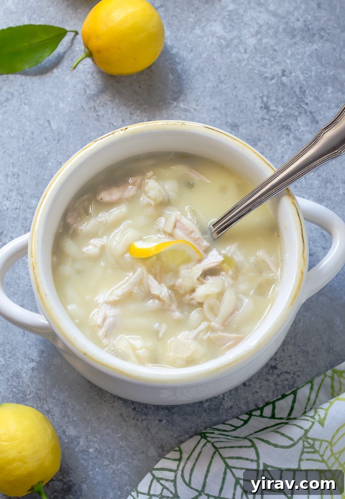 A close-up shot of slow cooker Greek avgolemono soup in a white bowl, with a spoon partially submerged, ready to be enjoyed.