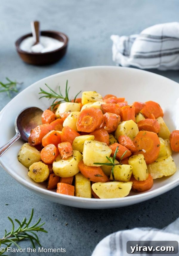 A serving of roasted carrots and parsnips in a white bowl, ready to be enjoyed, with a serving spoon.