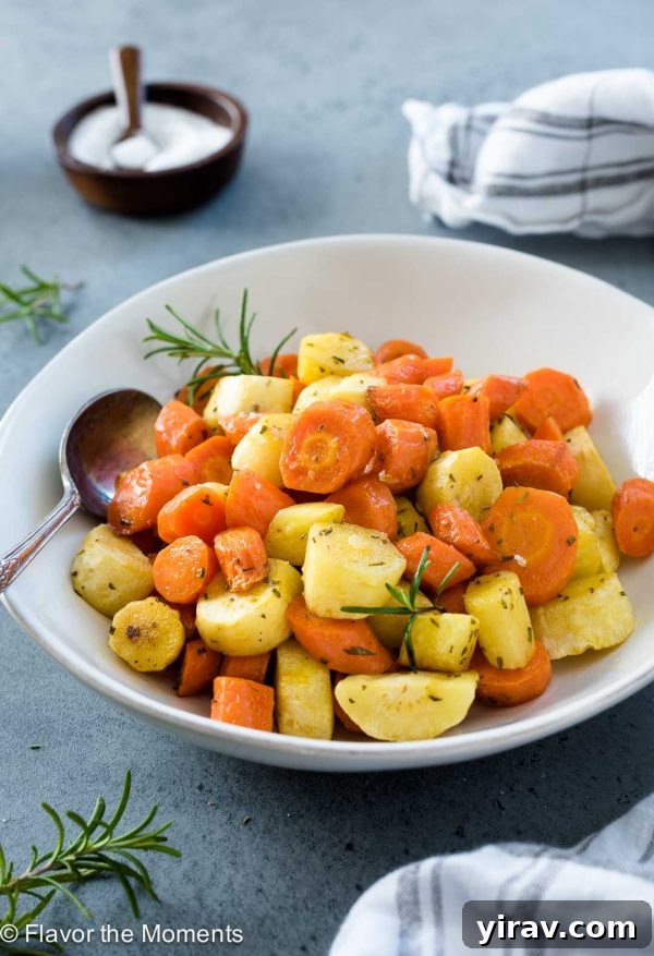 A close-up shot of roasted carrots and parsnips in a white serving bowl, showing their tender texture and caramelized edges.