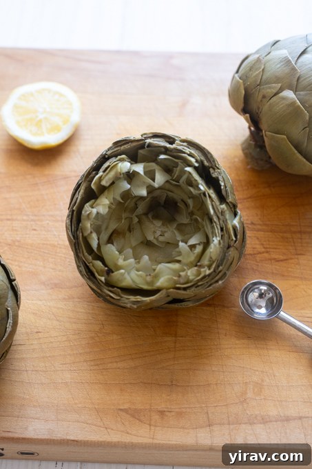Steamed artichoke on cutting board with leaves separated.