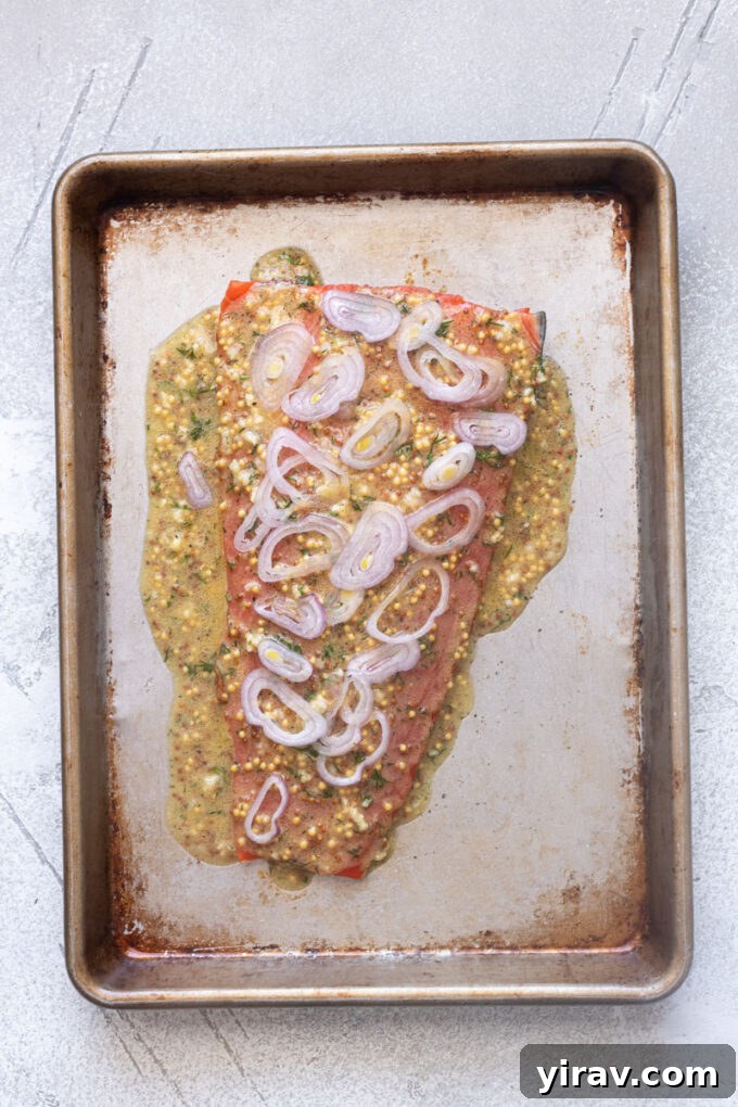 Wild salmon filet with citrus dijon sauce and shallots spread over the top.