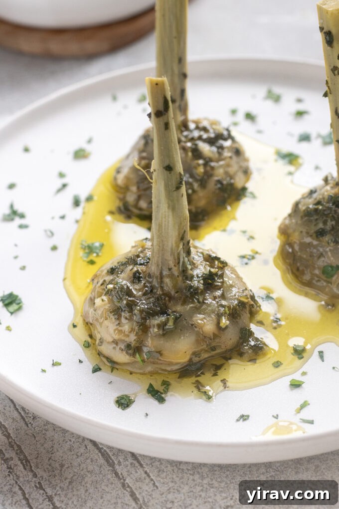 Roman artichokes on serving plate with garlic, fresh herbs and olive oil.