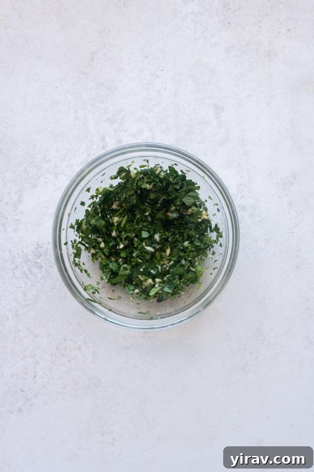 Minced garlic and chopped fresh parsley and mint in a small bowl.