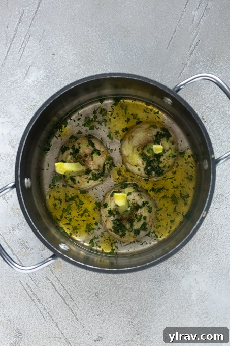Roman artichokes in pot with garlic and herb mixture, olive oil and water.