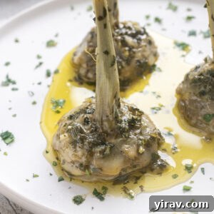 Roman artichokes on serving plate with garlic, fresh herbs and olive oil.