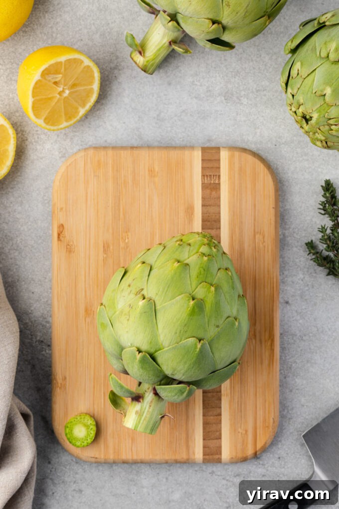 Artichoke with stem trimmed on cutting board.
