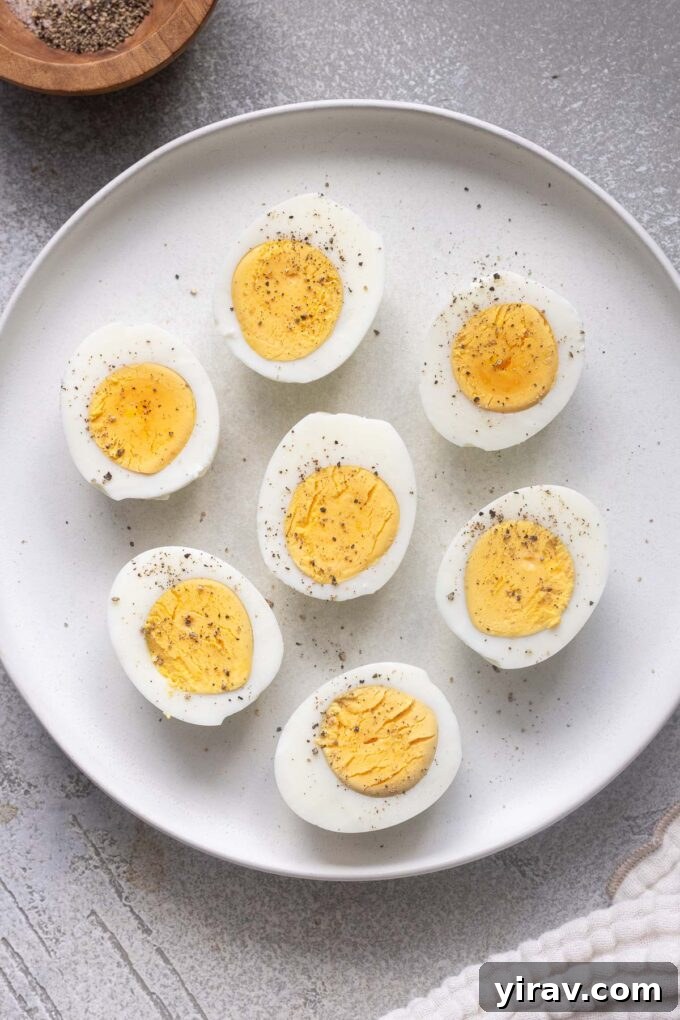 Air fryer hard boiled eggs cut in half with perfectly cooked yolks on a plate, ready to be enjoyed.