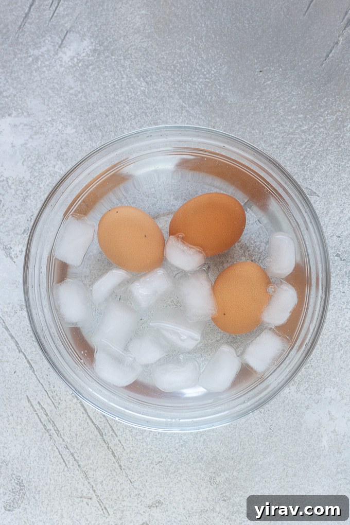 Air fryer hard boiled eggs submerged in a refreshing bowl of ice water.
