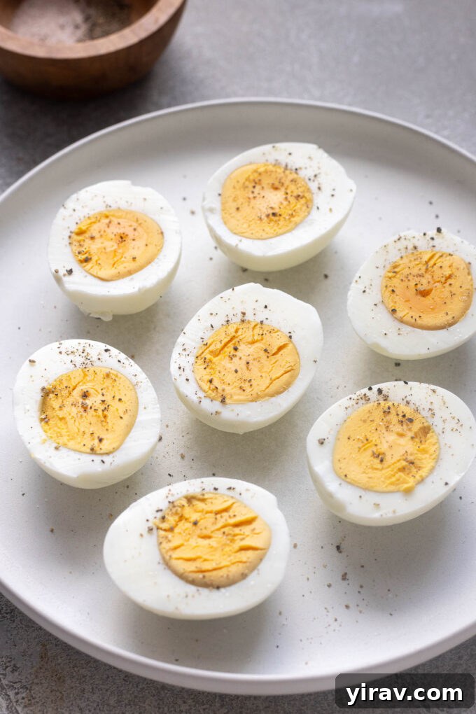 Halved air fryer hard boiled eggs on a plate with salt and pepper, showcasing their readiness to be eaten.