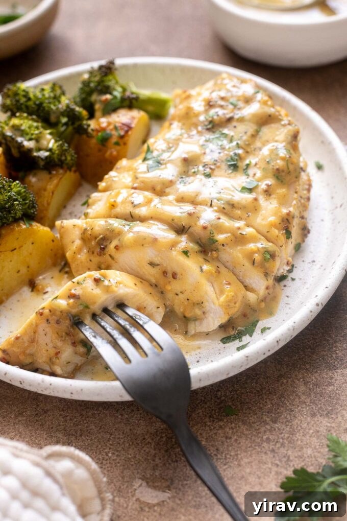 Plated honey mustard chicken with roasted vegetables on white plate.