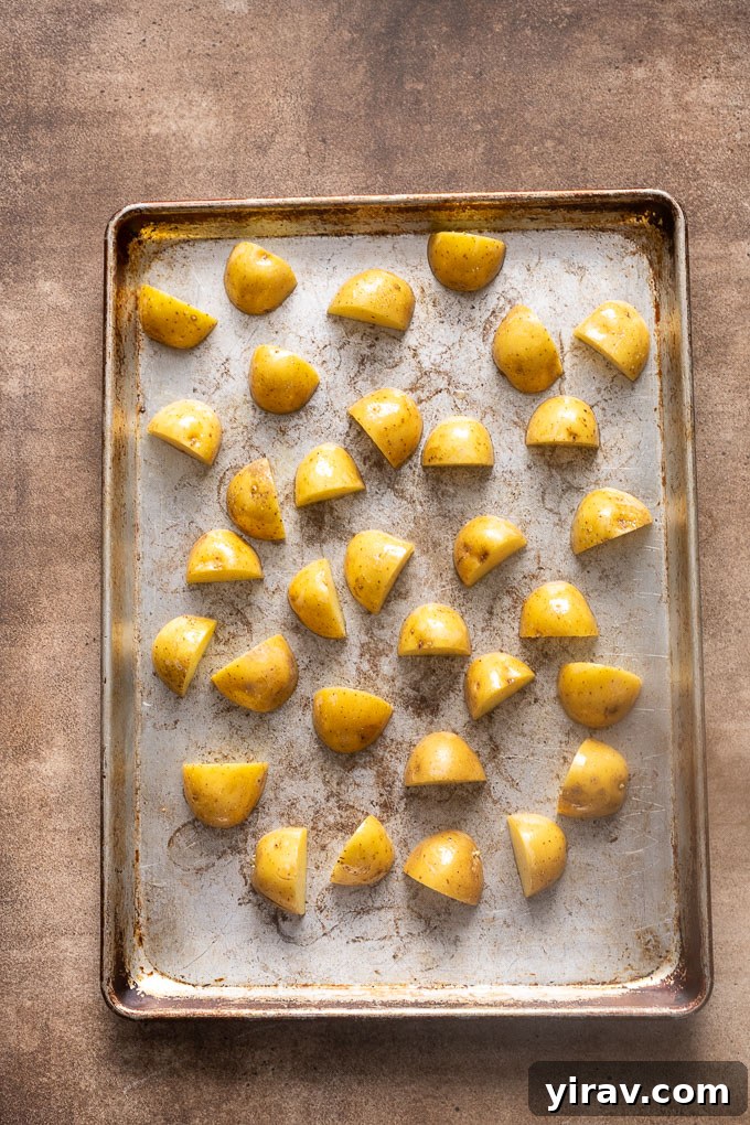Halved baby gold potatoes on a baking sheet before roasting