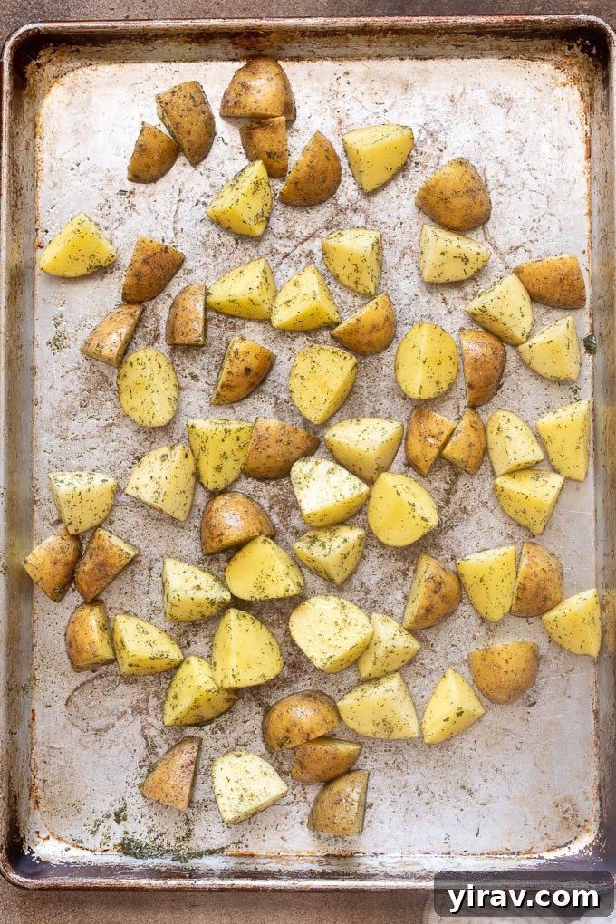 Baby gold potatoes coated with oil, ranch seasoning, salt and pepper on baking sheet.