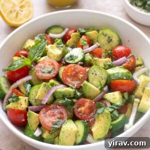 Cucumber tomato avocado salad in a bowl with basil and lemon vinaigrette.