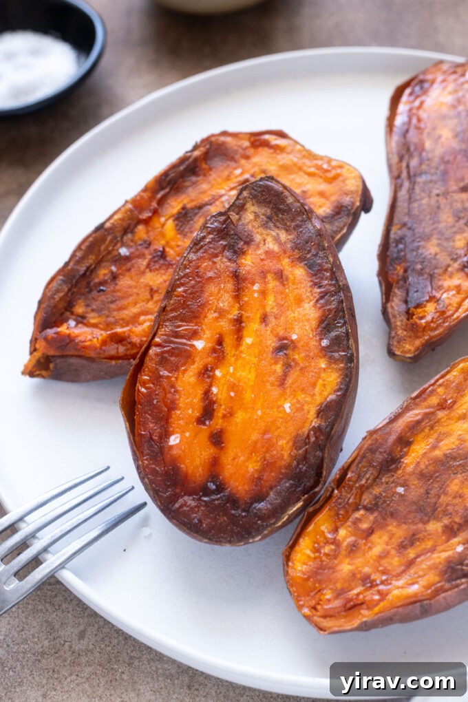 Roasted sweet potato halves with caramelized edges and sea salt on a plate.