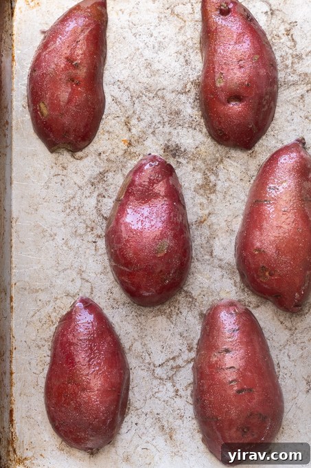 Sweet potatoes cut side down on baking sheet before roasting.