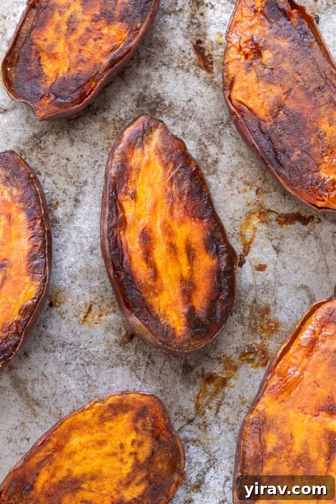 Caramelized roasted sweet potato halves on a baking sheet.
