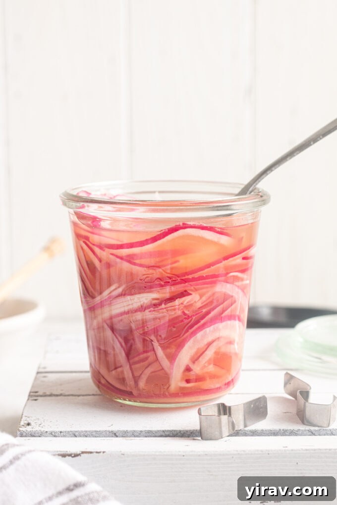 How to Make Quick Tangy Pickled Red Onions in 15 Minutes 2 Quick pickled red onions in a jar with a fork buried in it.