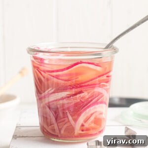 How to Make Quick Tangy Pickled Red Onions in 15 Minutes 14 Quick pickled red onions in a jar with a fork buried in it.