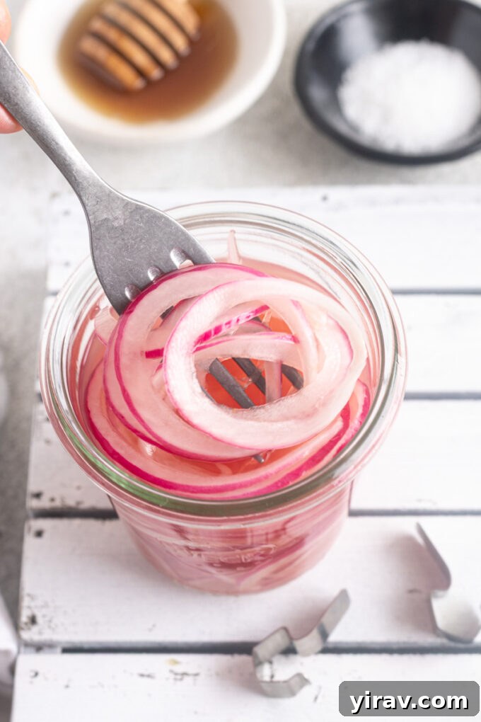 How to Make Quick Tangy Pickled Red Onions in 15 Minutes 3 Fork pulling quick pickled red onions out of a jar.