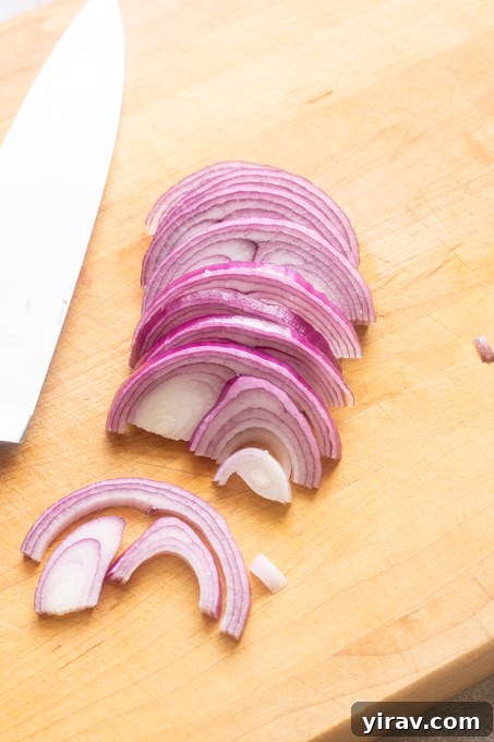 How to Make Quick Tangy Pickled Red Onions in 15 Minutes 6 Red onion sliced with a knife on a cutting board.