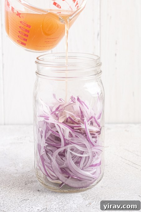 How to Make Quick Tangy Pickled Red Onions in 15 Minutes 9 Sliced onions in jar with brine pouring over the top.