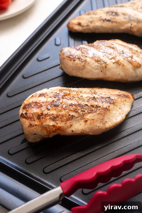 Grilled chicken for chicken pesto pasta salad on cutting board.