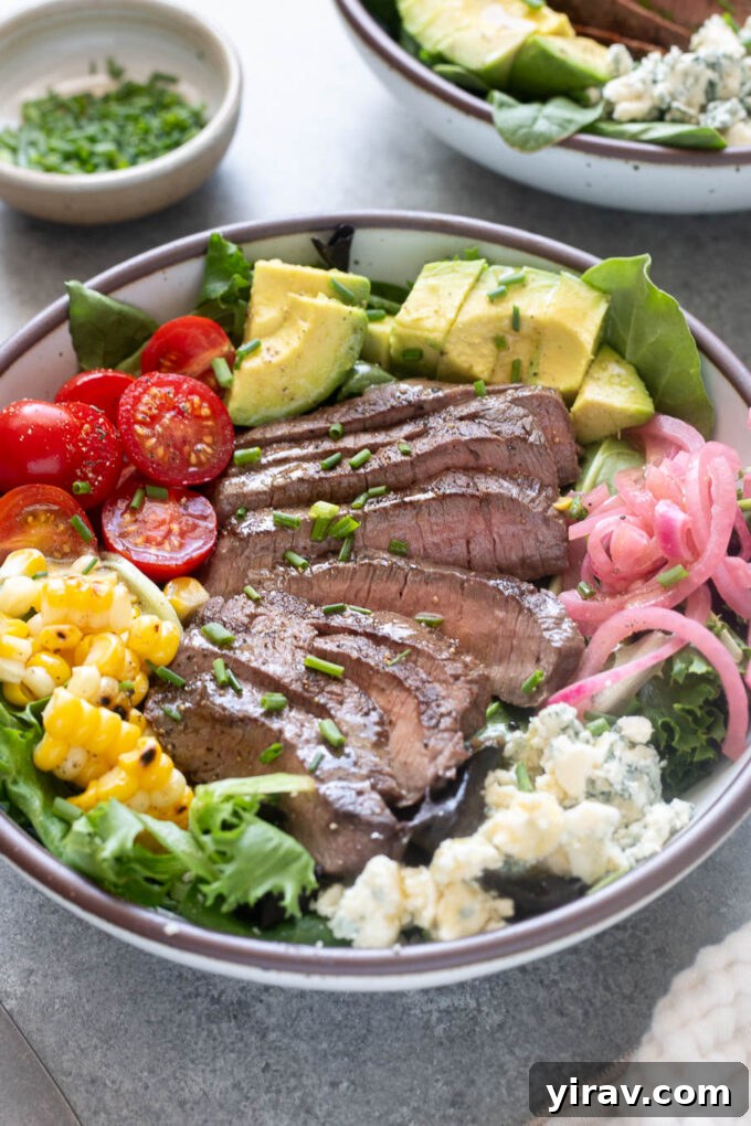 Close-up of grilled steak salad with sliced top sirloin, avocado, corn, tomatoes and blue cheese.