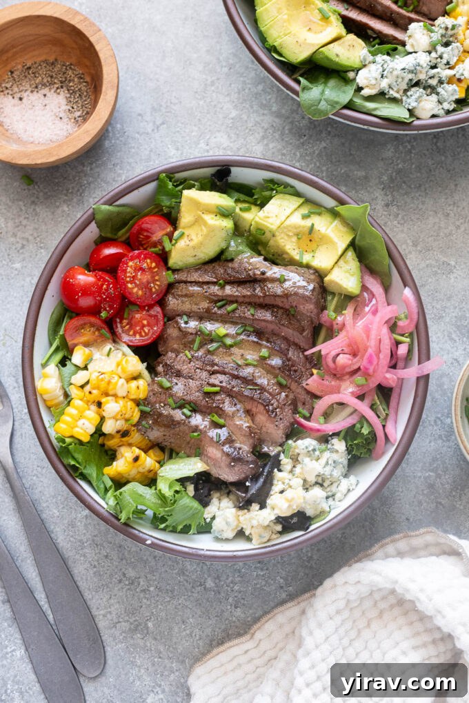 Summer steak salad with sliced steak, corn, avocado, tomatoes, blue cheese and pickled red onions.