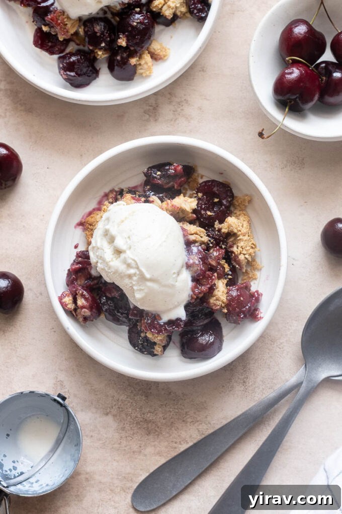 Individual serving of fresh cherry crisp topped with vanilla ice cream.