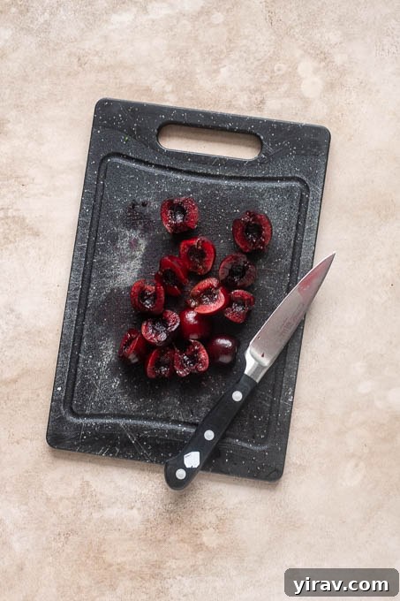 Halved cherries for fresh cherry crisp on cutting board.
