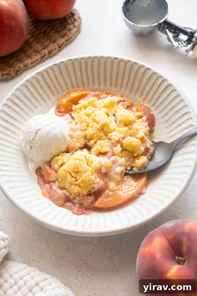 Fresh Peach Cobbler Recipe with Golden Biscuit Topping 11 Serving of fresh peach cobbler in a bowl with ice cream.