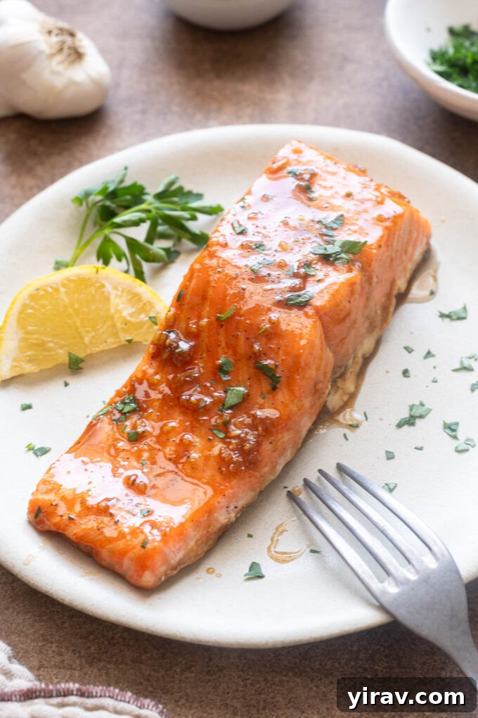 Honey Garlic Glazed Salmon Recipe 3 Honey garlic salmon filet on a plate with parsley and lemon.