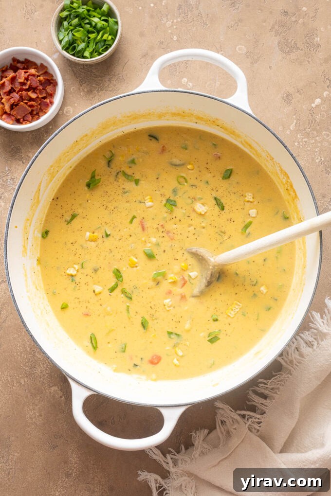 Creamy Zucchini and Corn Chowder with Crispy Bacon 3 Overhead view of homemade zucchini corn chowder with bacon and vegetables in a white Dutch oven.